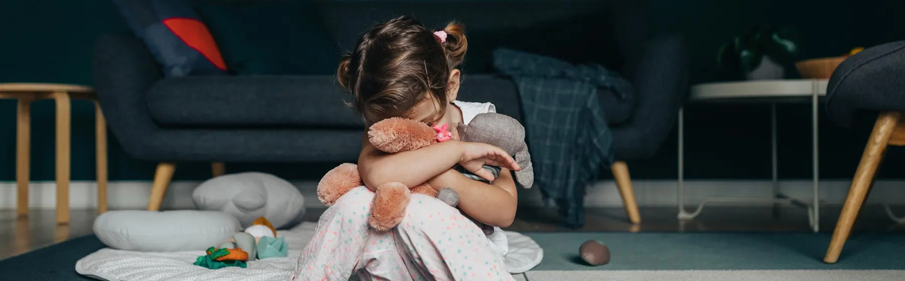 Enfant triste assise par terre avec son nounours