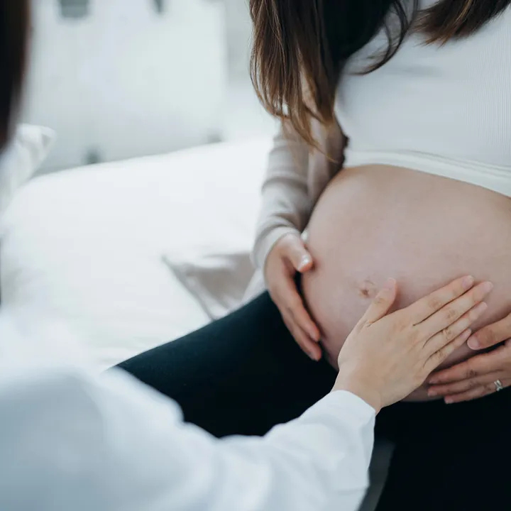 Sage-femme posant sa main sur le ventre d'une femme enceinte